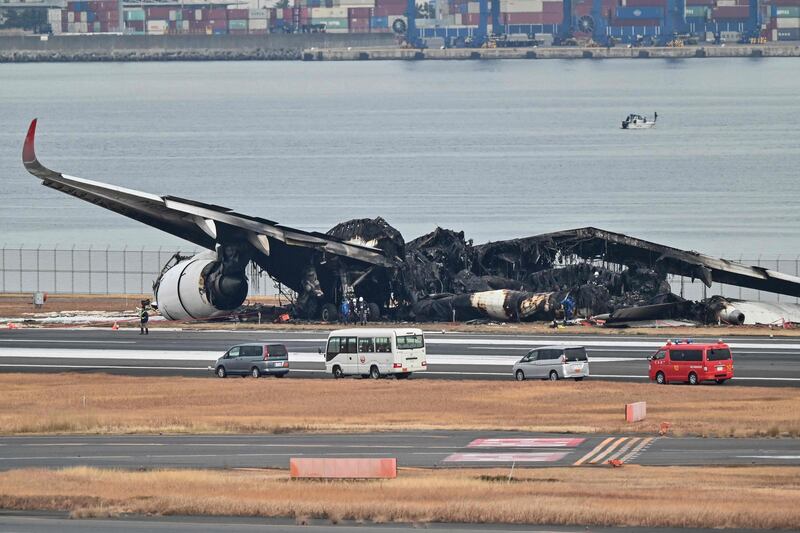 Officials inspect the wreckage of a Japan Airlines passenger plane at Tokyo International Airport at Haneda in Tokyo, the morning after it hit a coastguard plane on the ground. AFP