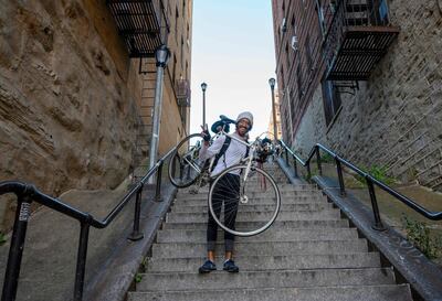 Elliott Raylassi, a local resident since 2001, carries his bike up the staircase in the Bronx, made famous by the movie "Joker," October 23, 2019 in New York. In the Bronx borough of New York, the 132 steps that connect Shakespeare Avenue to Anderson Avenue are usually rather quiet. But tourists from all over the world have flocked to them since they saw Joaquin Phoenix dancing on the steps in the blockbuster "Joker". / AFP / Don Emmert / TO GO WITH AFP STORY by Juliette MICHEL, "The Bronx, the "Joker" steps attract fans from all over the world"
