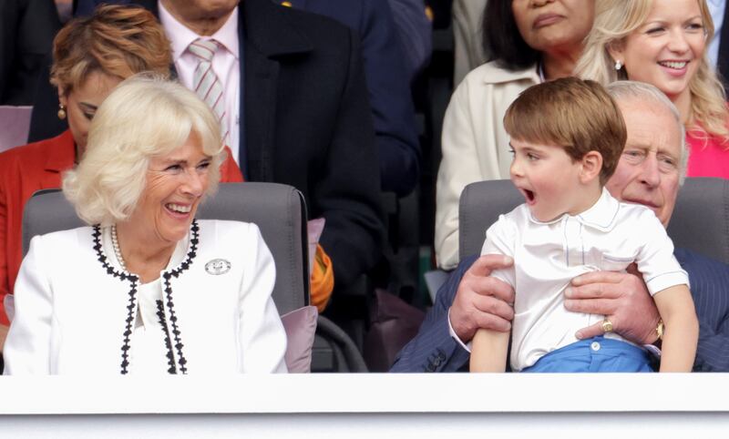The Duchess of Cornwall laughs with Prince Louis, who is on Prince Charles's lap, during the pageant. PA