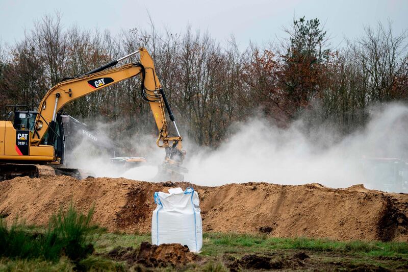 A bag of Calcium oxide is seen in the foreground as an excavator buries dead mink in ditches while members of Danish health authorities are assisted by members of the Danish Armed Forces in disposing of dead mink in a military area near Holstebro in Denmark on Monday, November, 9 2020.   Danish mink will be buried in mass graves on military land as the country's incinerators and rendering plants struggle to keep up, the Danish environmental and health authorities announced. Denmark will cull about 17 million mink after a mutated form of coronavirus that can spread to humans was found on mink farms.  - Denmark OUT
 / AFP / Ritzau Scanpix / Morten Stricker
