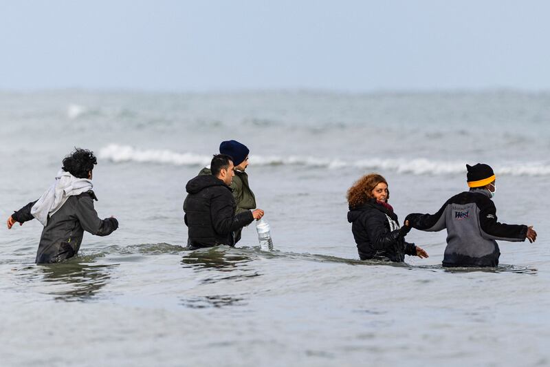 Migrants walk into the sea. 