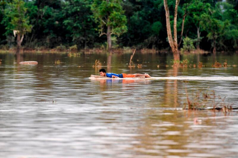 A man floats on flood water at a village in Sanamxai, Attapeu province. AFP