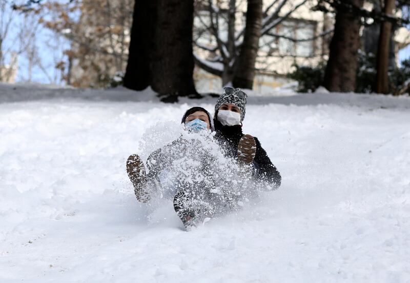 Aysegul Cepoglu, rear, and Ahmet Efe Isik slide down the hill at snow-blanketed Seymenler Park, in Ankara, Turkey, on Wednesday, February 17, 2021. AP Photo