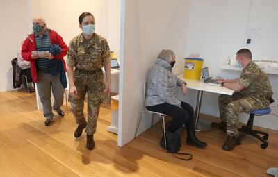 Edinburgh residents,James Logan (L) and Sylvia Campbell (2R) receive a Covid-19 vaccine from military personel at a temporary vaccination centre set up at the Royal Highland Showground near Edinburgh, Scotland, on February 4, 2021, as more than 200 military personnel support the vaccination rollout across Scotland.  Oxford University announced on Thursday it will launch a medical trial alternating doses of Covid-19 vaccines created by different manufacturers, the first study of its kind. / AFP / POOL / Andrew Milligan
