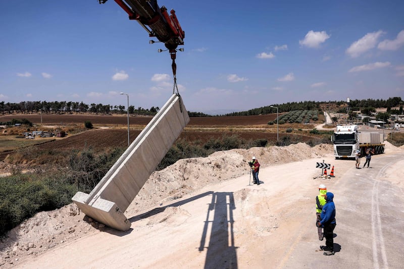 A crane hoists a concrete slab into place as Israel reinforces a wall separating it from the West Bank. All photos: AFP