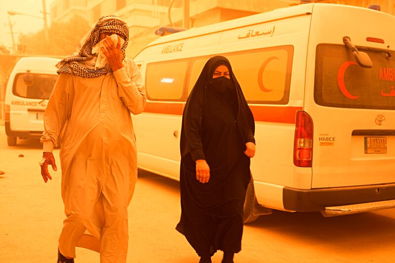People walk on a street in Baghdad during a sandstorm. AP
