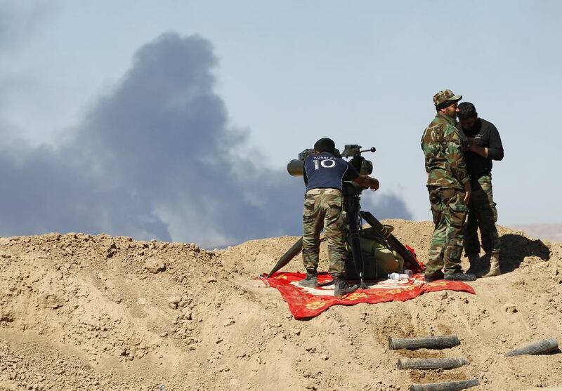 Smoke rises from the Ajil oil field as Iran-backed militiamen gather in Al Hadidiya, south of Tikrit, en route to the ISIL-controlled town of Al Alam on March 6, 2015. Thaier Al Sudani/Reuters