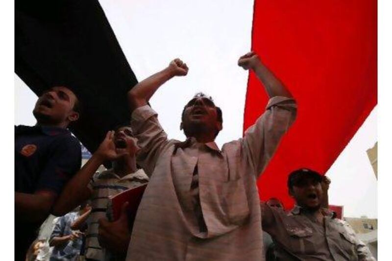 Anti-government protesters shout slogans as they march under a large Yemeni flag during a demonstration to demand the departure of President Ali Abdullah Saleh in the southern city of Taiz yesterday. Khaled Abdullah / Teuters