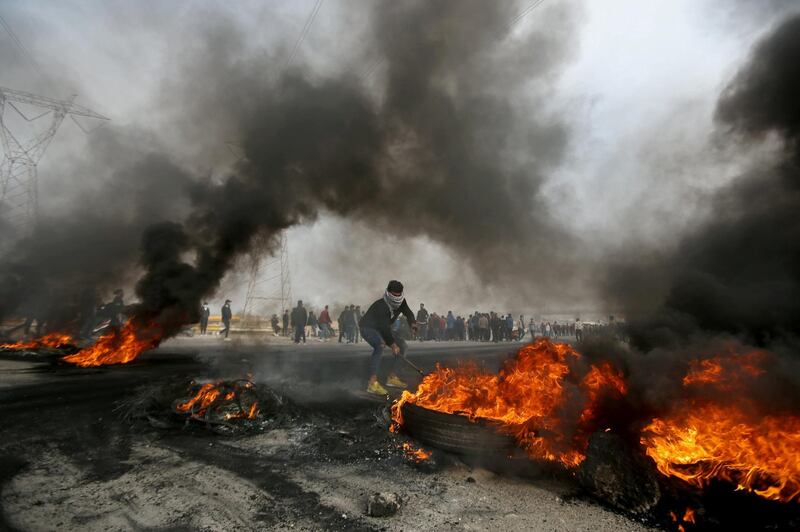 An Iraqi demonstrator moves burning tires during anti-government protests in Basra, Iraq, December 20, 2020. REUTERS/Essam al-Sudani