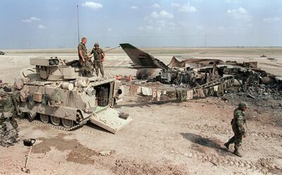 US soldiers stand guard 26 March 1991 at the Nasiriyah air base, 300 kms south of Baghdad, beside a destroyed Iraqi Soviet-made Mig-22 jet fighter, where combats between Iraqi Ch'ite rebels and Iraqi army are going on. (Photo by MANOOCHER DEGHATI / AFP)