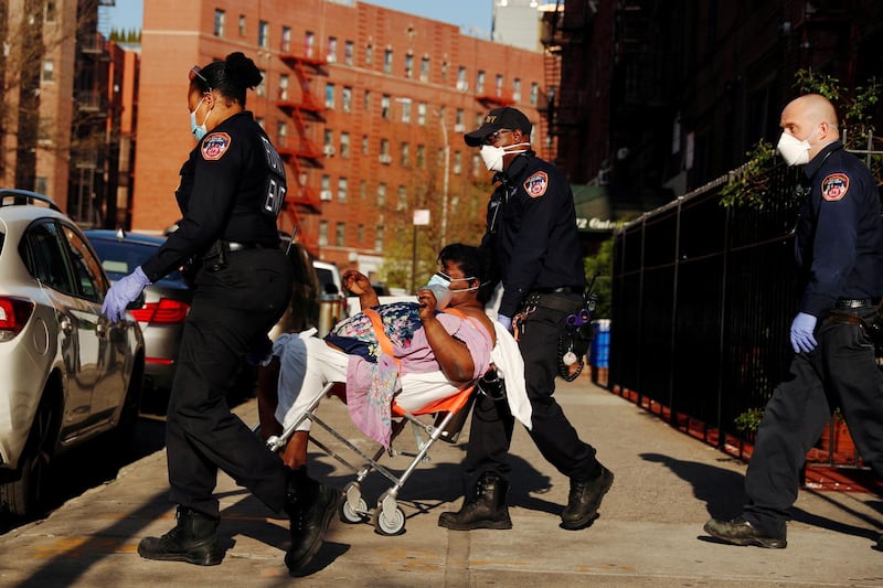 A New York City Fire Department (FDNY) Emergency Medical Technician (EMT) wearing personal protective equipment assist a woman who was having difficulty breathing during ongoing outbreak of the coronavirus disease (COVID19) in New York, U.S. REUTERS