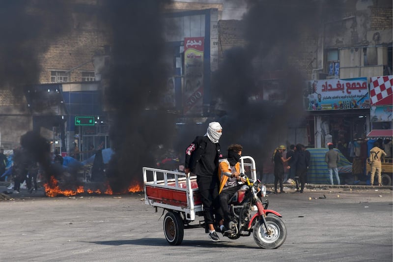 Iraqi protesters run for cover during clashes with police during anti-government demonstrations in the city of Nasiriyah in the Dhi Qar province in southern Iraq.  AFP