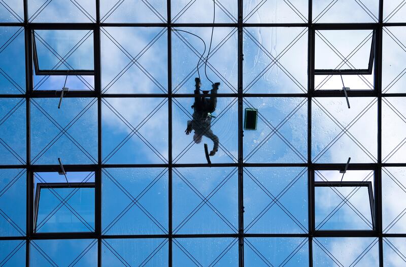 Cleaner Andreas Reimann is silhouetted against the blue sky when cleaning the roof of the  "World Trade Center" in Dresden, eastern Germany. Monika Skolimowska /dpa via AP