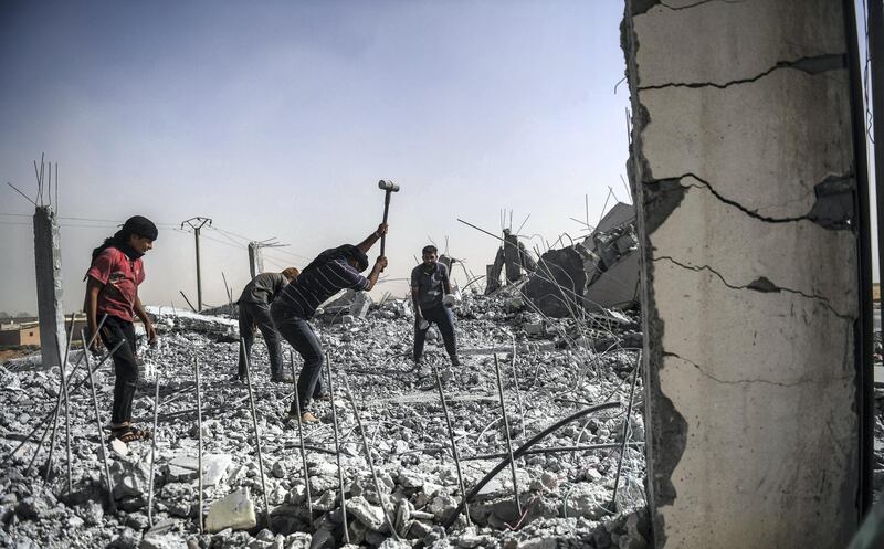 Syrians clear up the rubble of their houses that were destroyed during clashes on the outskirts of Raqa, on July 19, 2017, as Syrian Democratic Forces, a Kurdish-Arab alliance, are battling to retake the city from Islamic State (IS) group fighters. (Photo by BULENT KILIC / AFP)