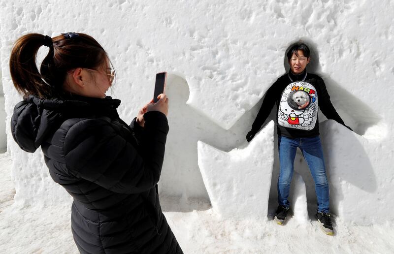 A woman takes a picture of her husband creating snow angels  in Pyeongchang, South Korea. Eric Gaillard / Reuters