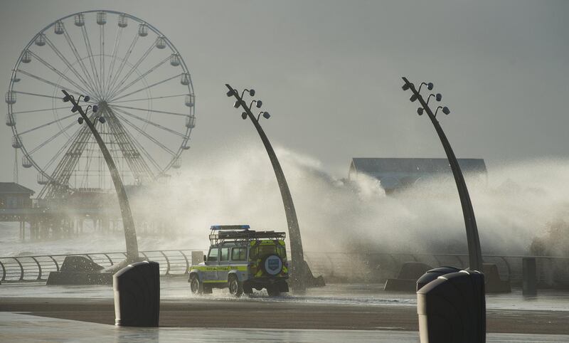 A beach patrol vehicle drives past waves crashing against the breakwater in Blackpool. Peter Powell / EPA