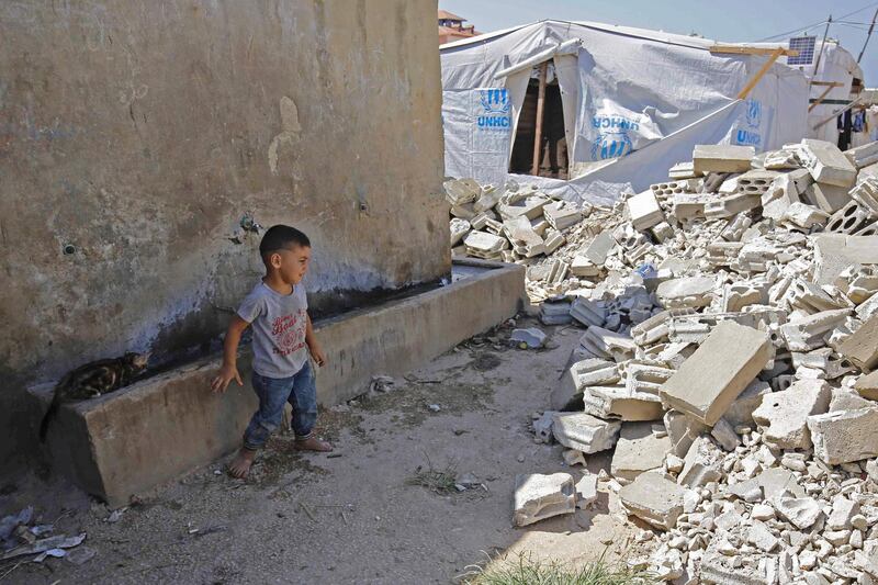 TOPSHOT - A Syrian child looks at the rubble of demolished concrete walls at a make-shift camp in the town of Rihaniyye in Lebanon's Akkar governorate on August 9, 2019. A coalition of international NGOs said the Lebanese army raided Syrian refugee settlements destroying a number of tents, urging authorities to stop the demolitions. Troops raided more than 30 settlements in the northern Akkar region today and at least five more tomorrow. / AFP / Ibrahim CHALHOUB
