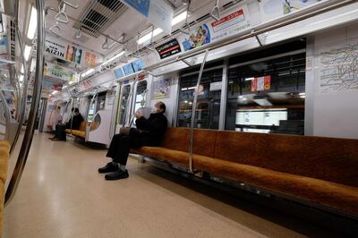 A man wearing a face mask sits in a quiet car in the subway in Tokyo on March 30, 2020.  / AFP / Kazuhiro NOGI
