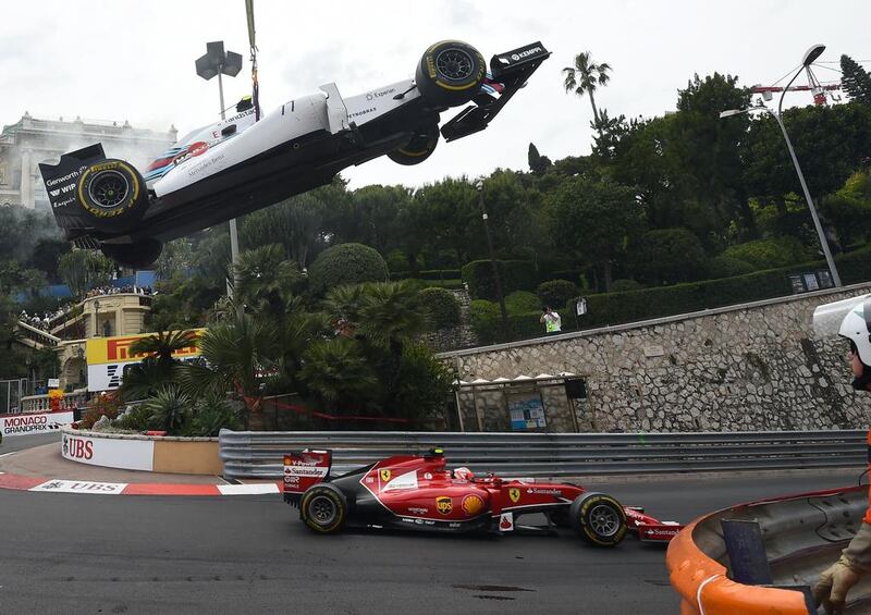 Ferrari's Kimi Raikkonen drives as a crane lifts the car of Williams driver Valtteri Bottas after he crashed at the Monaco Grand Prix. Anne-Christine Poujoulat / AFP