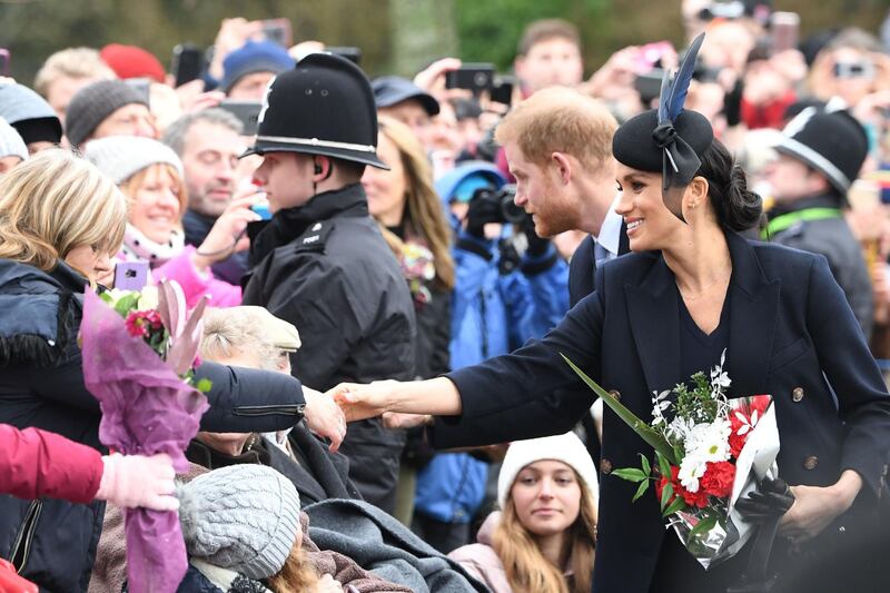 Meghan, Duchess of Sussex (R) and Britain's Prince Harry, Duke of Sussex greet the crowds after the Royal Family's traditional Christmas Day service at St Mary Magdalene Church in Sandringham, Norfolk, eastern England. AFP