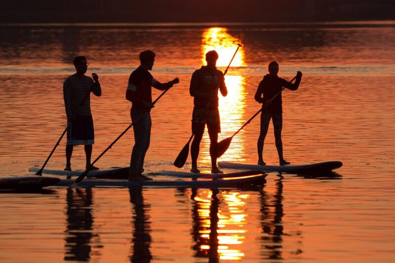 The sun rises behind stand-up paddlers at the river Alster in Hamburg, northern Germany. Christian Charisius / dpa via AP