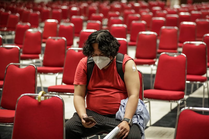 A man sits and waits after receiving a Pfizer-BioNTech Covid-19 booster vaccine in Jakarta, Indonesia. EPA