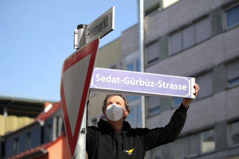 A man sets up a street sign with the name of Sedat Guerbuez, one of nine victims of the Hanau shootings. AFP