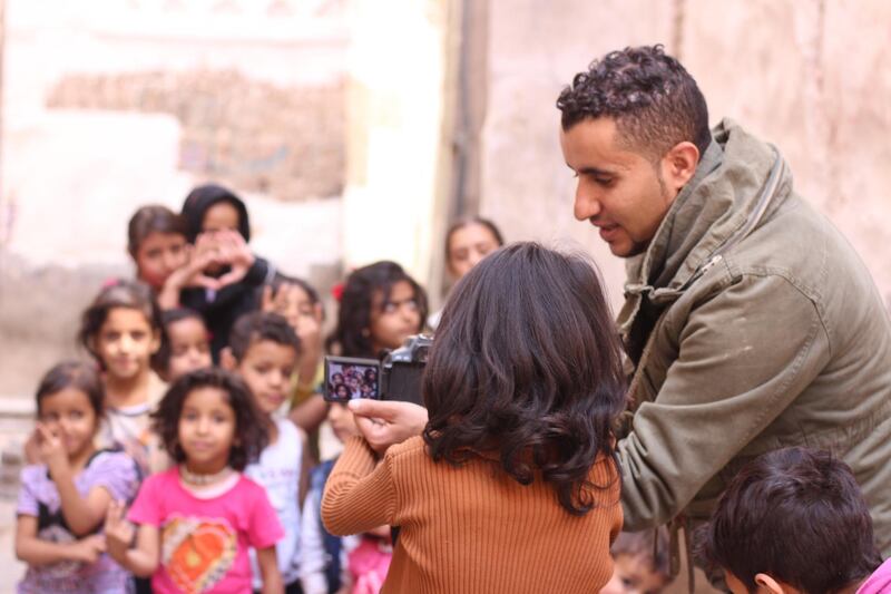 Ali Alsonidar showing children some photos he took of them. Ali Alsonidar