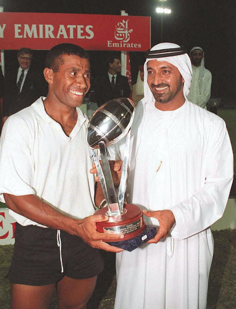 Fiji's captain Waisale Serevi (L) and Sheikh Ahmed bin Saeed Al Maktoum, head of Dubai Civil Aviation and Chairman of Emirates Airlines, hold the Dubai Rugby Sevens trophy 23 November after Fiji defeated world champions South Africa 33-12 in the final of the 3-day tournament. 
Both teams, together with Tonga, Wales, Zimbabwe, Scotland, the US, and Morocco  qualified for the World Cup Rugby Sevens finals to be held in Hong Kong in March next year. / AFP PHOTO / JORGE FERRARI