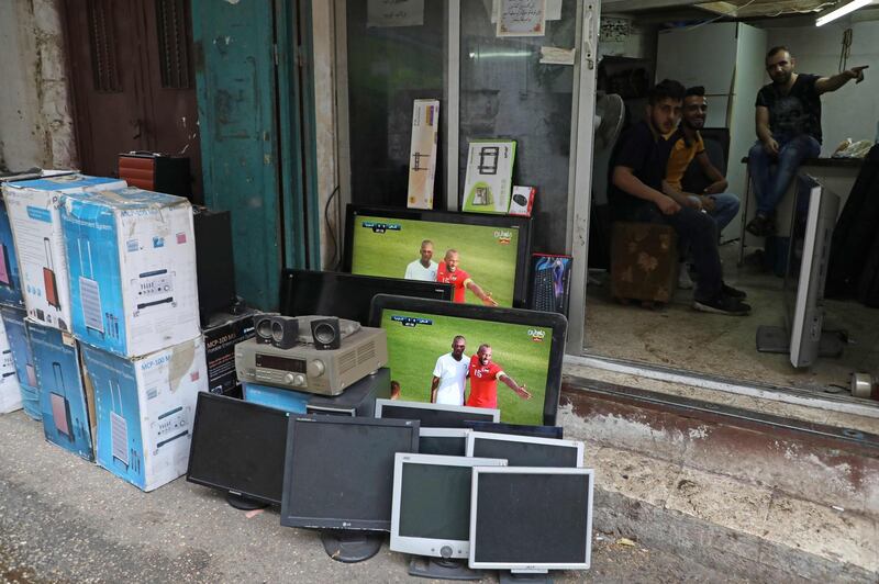 The World Cup 2022 Asian qualifying match between Palestine and Saudi Arabia is shown on a television screens outside a shop the northern Israeli occupied West Bank city of Nablus. AFP