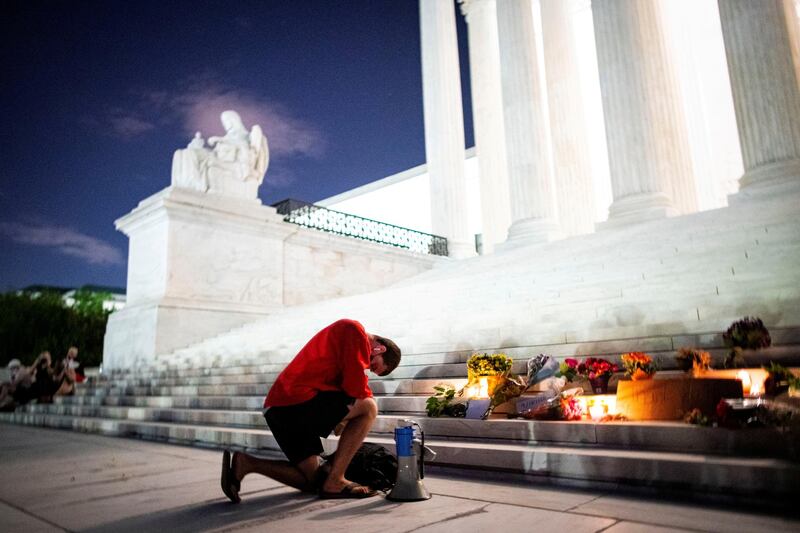 A man kneels as he brings a megaphone to a vigil on the steps of the US Supreme Court following the death of US Supreme Court Justice Ruth Bader Ginsburg, on September 18, 2020. Reuters