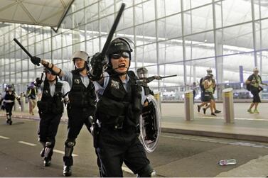 Policemen with batons and shields shout at protesters during a demonstration at the airport in Hong Kong. AP Photo