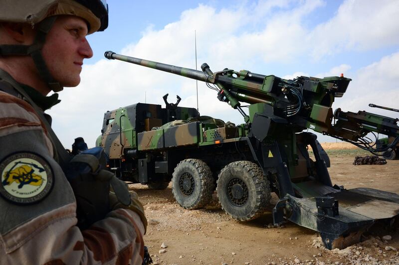 A French soldier engaged in the "Operation Chammal", the French military operation within "Operation Inherent Resolve", the international coalition against the Islamic State (IS) group, stands guard in front of a wheeled 155 mm gun-howitzer CAESAR system (trucks equipped with an artillery system), on February 9, 2019, near Al-Qaim, a few kilometres away from the last scrap of territory held by IS in eastern Syria. The US-backed Syrian Democratic Forces said on February 9, 2019 it had begun the "final battle" to oust the Islamic State group from the last scrap of territory it holds in eastern Syria. / AFP / Daphné BENOIT
