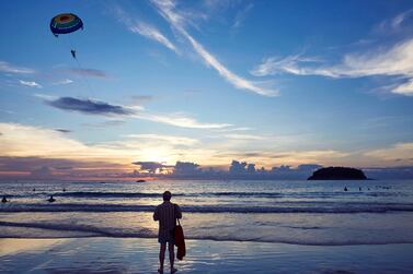 KATA BEACH, PHUKET, THAILAND - 2017/11/21: A beachgoer watches parasailing off the beach in Phuket. Tourists can take short parasailing flights from the beach out toward the small island, Koh Pu, and back again. Phuket attracts more than 5 million tourists each year who flock there for it's picturesque beaches. (Photo by Craig Ferguson/LightRocket via Getty Images)
