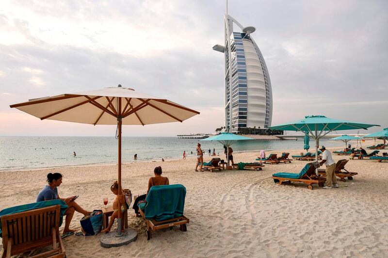 Beach-goers lie on lounge chairs by the shoreline near Burj Al Arab hotel in Dubai on May 20, as Covid-19 measures are eased. Karim Sahib / AFP
