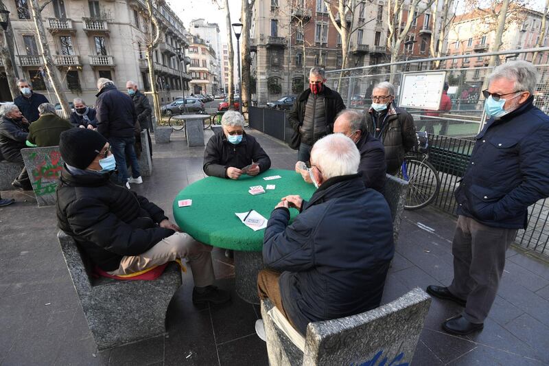 Elderly people wearing face masks play cards in a small park in Milan. EPA