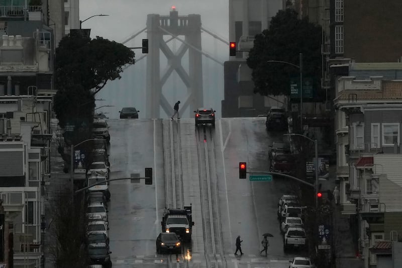 Drenched pedestrians cross California Street in San Francisco during the storm. AP