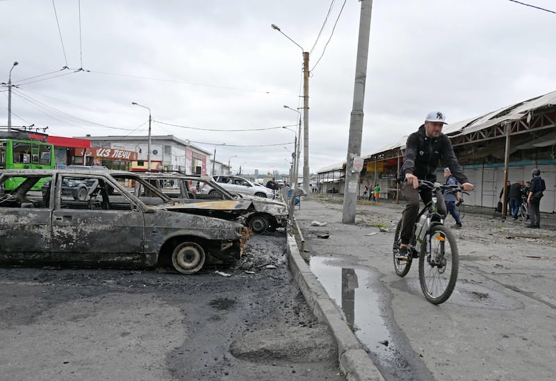 A cyclist rides past burnt cars after a Russian rocket strike in Kharkiv. AFP