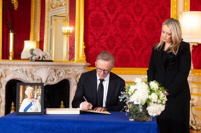 Prime Minister of Australia Anthony Albanese signs a book of condolence to Queen Elizabeth as his partner Jodie Haydon looks on. AP