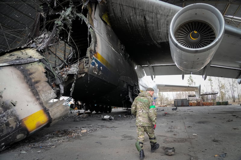 A Ukrainian officer searches for unexploded explosives as he passes by an Antonov An-225, the world's biggest cargo aircraft, destroyed during the war on the outskirts of Kyiv. AP