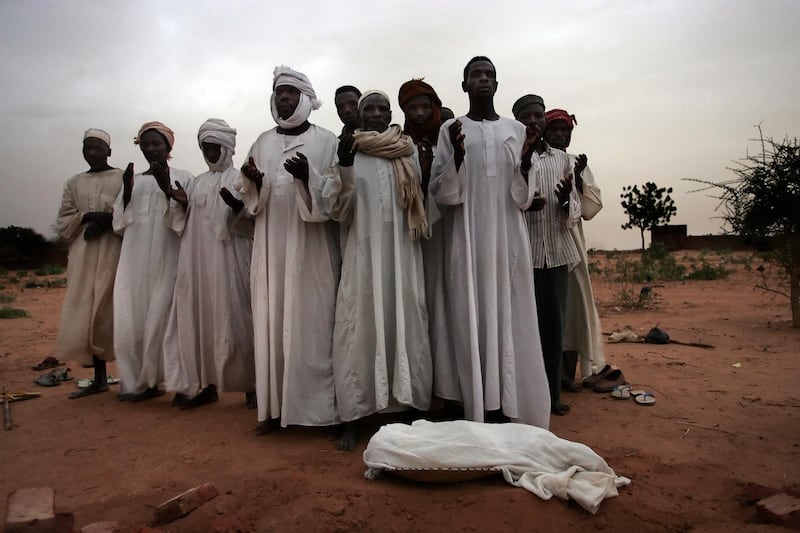 Relatives mourn over the body of 1-year-old Ali, who died of malnutrition 21 June 2004 in a refugee camp in El-Geneina in the Darfour, Sudan. More than 80,000 displaced people reached Mornay to try to escape ethnic violence in the Darfur region. After surviving massacres carried out by pro-government militias on their villages, these refugees are now virtual prisoners in the camp as the same militias now control the camp's periphery conducting violent attacks and rapes on villagers who go out looking for food and essential items according to Medecins Sans Frontiers (MSF) (Doctors without Borders) the French medical charity.  AFP PHOTO/MARCO LONGARI (Photo by Marco LONGARI / AFP)