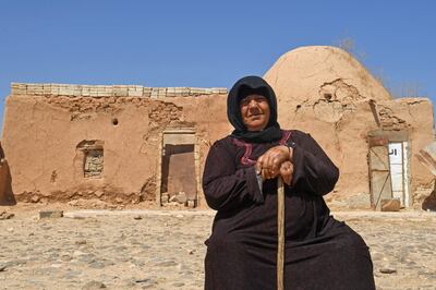 A woman sits outside her traditional mud-brick house in the village of Umm Amuda Kabira in Syria's Aleppo province. AFP