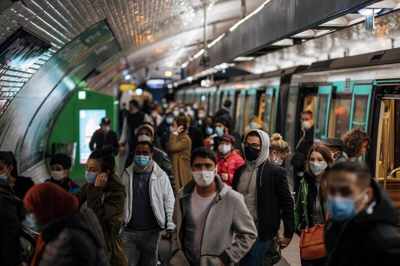 Commuters wearing face masks walk on the platform of a Paris subway. AP Photo