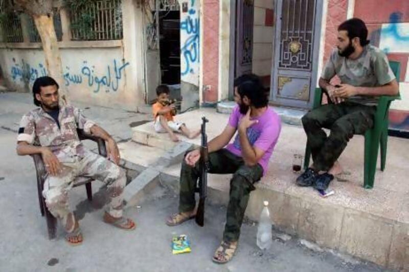 A boy aims his toy gun as he sits with members of the Free Syrian Army in Deir Al Zor.