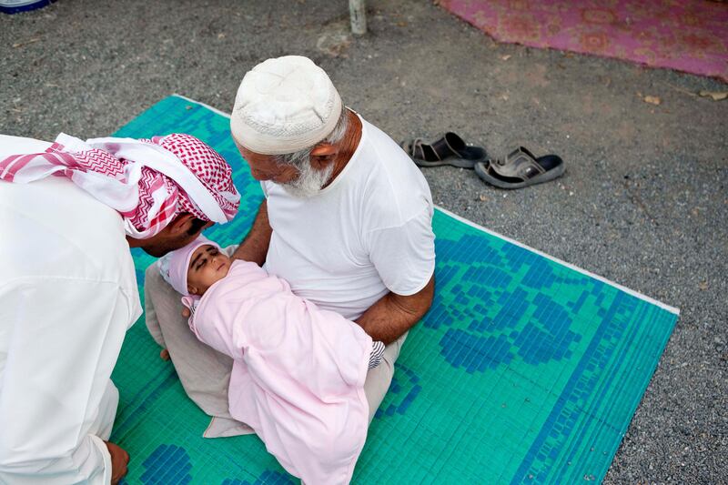 June 17, Ali Abdullah Ali Al Dhagmani holds his two month old sun while Aid Mater kisses his forehead as a sign of respect and blessing. Ali and his family lives on a traditonal Emirate farm in Wadi Al Tuwa.  June 1, Ras Al Khaimah, United Arab Emirates. (Photo: Antonie Robertson/ The National)