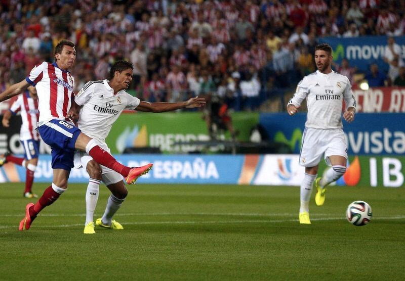 Atletico Madrid's Mario Mandzukic kicks to score past Real Madrid's Raphael Varane, left, and Sergio Ramos, right, during the Spanish Super Cup on Friday. Juan Medina / Reuters