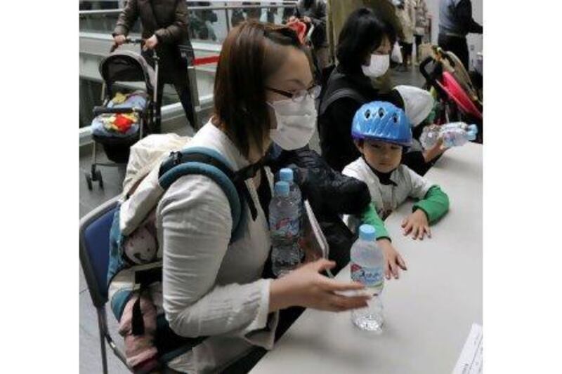 Mothers with children under 12 months receive bottles of water at a Tokyo ward office yesterday.