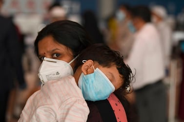 An Indian woman carries a sleeping child as she waits at the Dubai International Airport before leaving the Gulf Emirate on a flight back to her country, on May 7, 2020, amid the novel coronavirus pandemic crisis. The first wave of a massive exercise to bring home hundreds of thousands of Indians stuck abroad was under way today, with two flights preparing to leave from the United Arab Emirates. India banned all incoming international flights in late March as it imposed one of the world's strictest virus lockdowns, leaving vast numbers of workers and students stranded. / AFP / Karim SAHIB