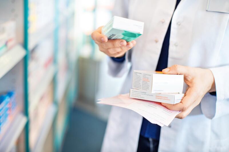 Closeup of pharmacist's hands taking medicines from shelf at the pharmacy. Getty Images