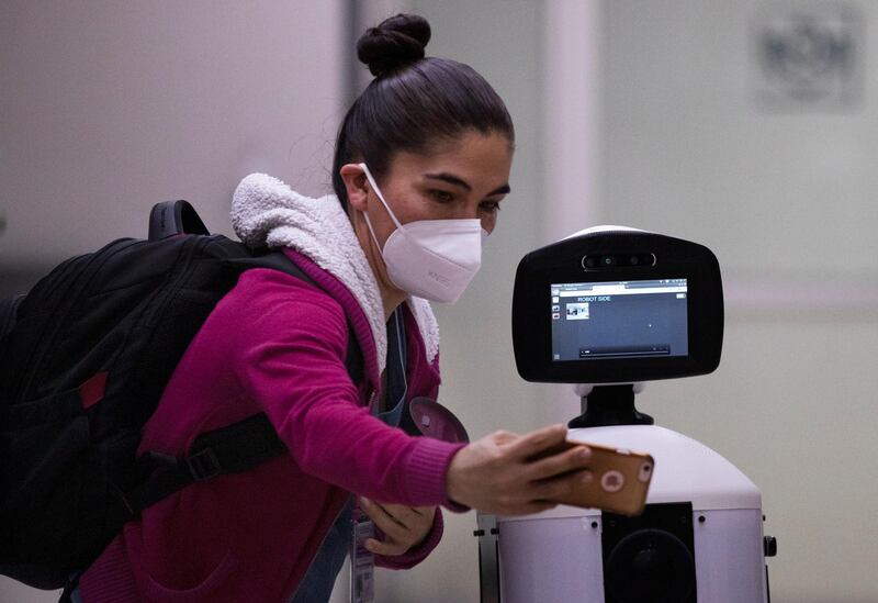 A healthcare worker poses for a photo with Laluchy Robotina, a robot designed to aid in the mental health of patients infected with the new coronavirus, in the COVID-19 ward at 20 de November National Medical Center in Mexico City, Friday, Sept. 25, 2020. The 1.4-meter-tall robot that moves around on wheels visiting COVID-19 patients, is equipped with a camera and display screen which allows the patients to visit with relatives and to also communicate with healthcare workers, helping to reduce the risk of infection. (AP Photo/Marco Ugarte)